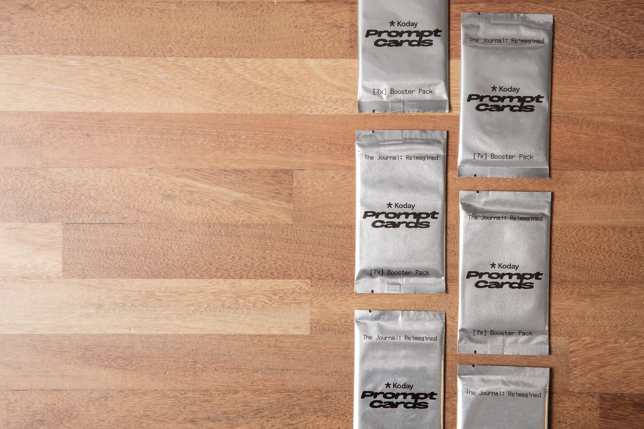 Multiple Koday Prompt Cards booster packs arranged on a wooden surface