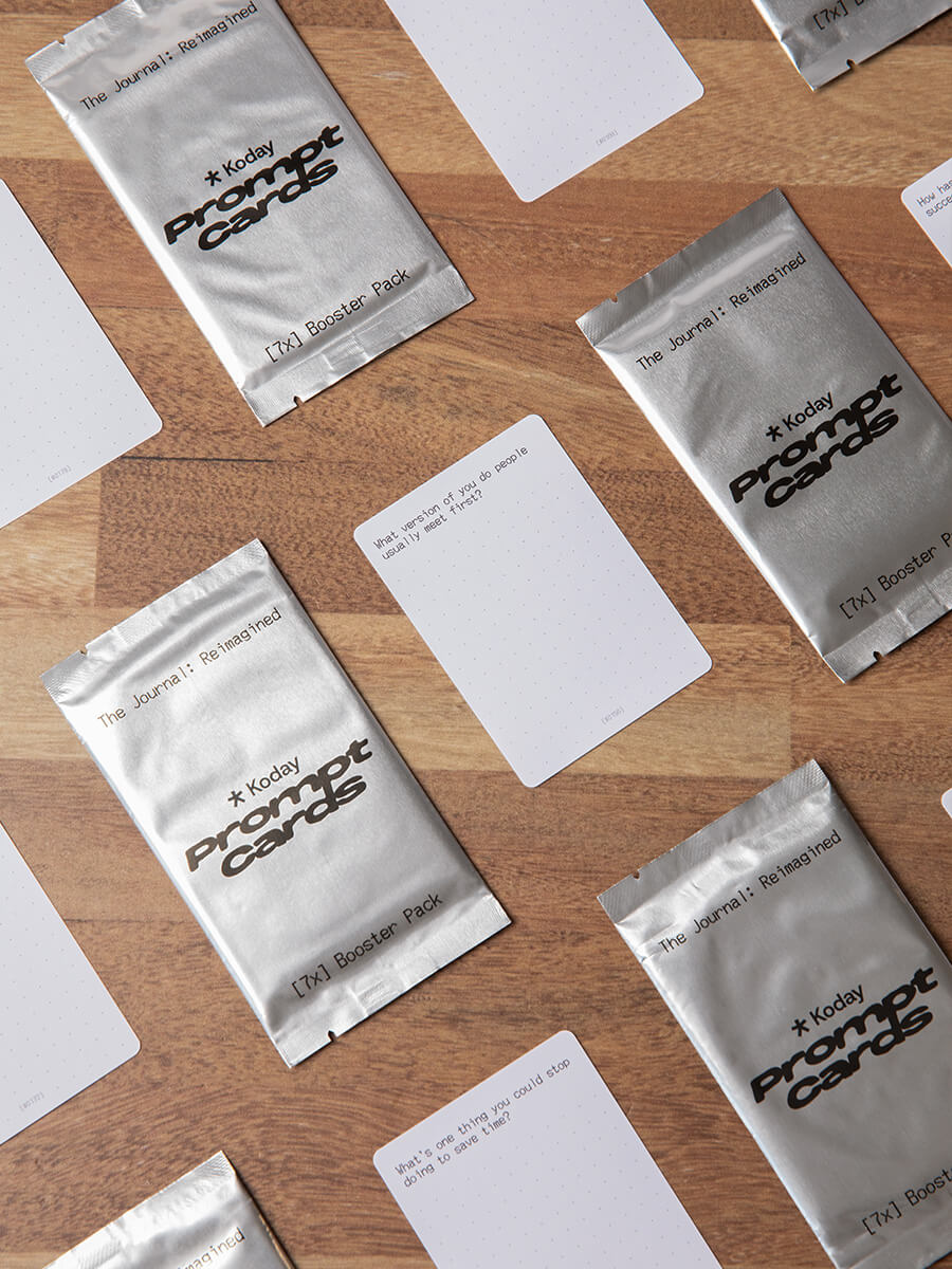 Koday Prompt Card packs and cards arranged in a checkerboard pattern on a wooden surface